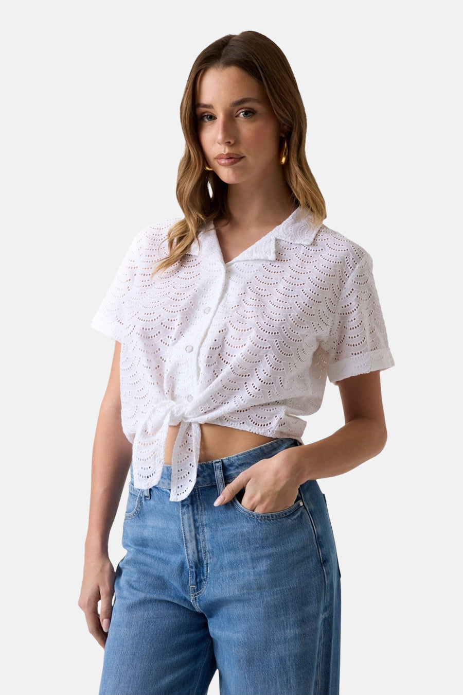 Wit blouse met korte mouwen van Guess met geschulpte oogjes, gestrikt aan de taille en gedragen met een spijkerbroek.