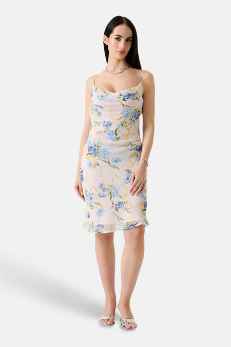 Multikleuren jurk van Guess, met blauw en geel bloemenpatroon, gedragen met zilveren schoenen en een ketting.