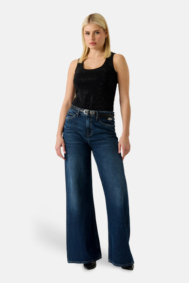 Zwart mouwloos T-shirt van Guess met glanzend textuurpatroon, gedragen met een wijde jeans en een riem.