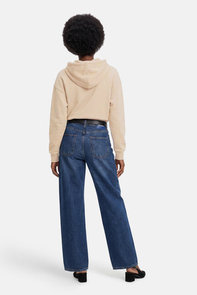 Sweat à capuche beige de Guess®, vu de dos, porté avec un jean large bleu et des chaussures noires.