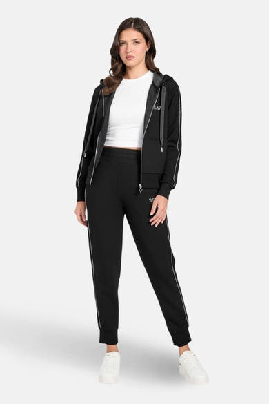 Zwart trainingspak van Guess, bestaande uit een hoodie met rits en een joggingbroek, met witte streepdetails.