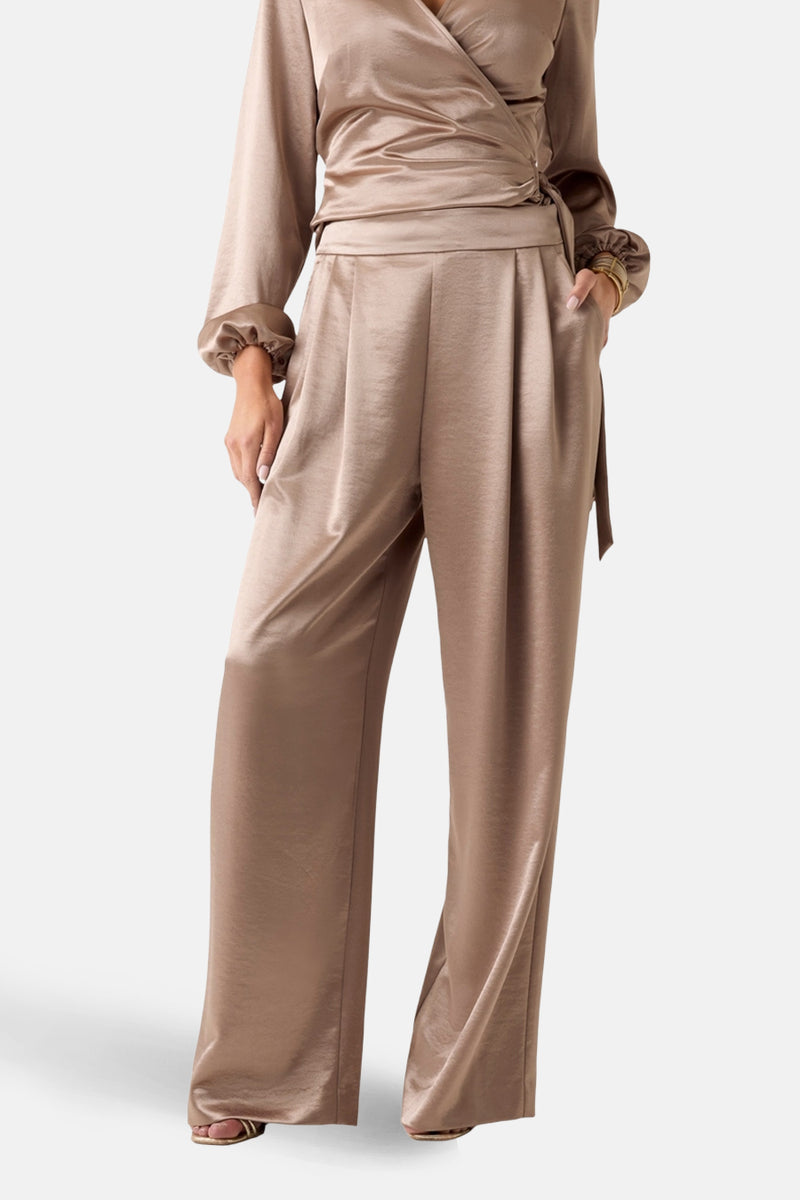 Gouden Guess® broek, wijdvallend met plooien en bijpassende riem, gedragen met een bijpassend topje.