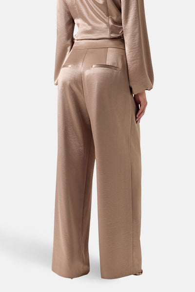 Gouden Guess-broek, met paspelzakken achter, gedragen met een bijpassend topje, achterzicht.