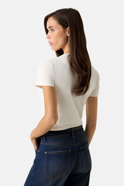 T-shirt à manches courtes blanc de Guess®, ajusté et porté par une femme vue de dos avec un jean foncé.