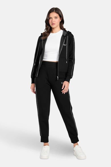 Zwarte Guess bodywarmer met ritssluiting gedragen over een wit T-shirt en een bijpassende joggingbroek.