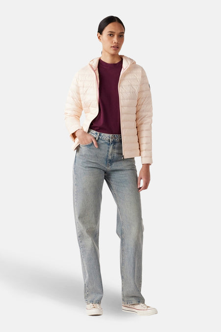 Veste de pluie rose de JOTT, portée avec un jean décontracté et des baskets en toile.