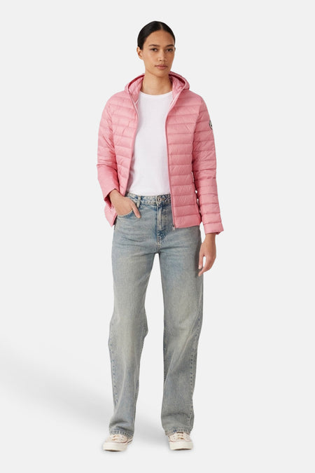Veste de pluie rose de JOTT, portée avec un t-shirt blanc et un jean décontracté.
