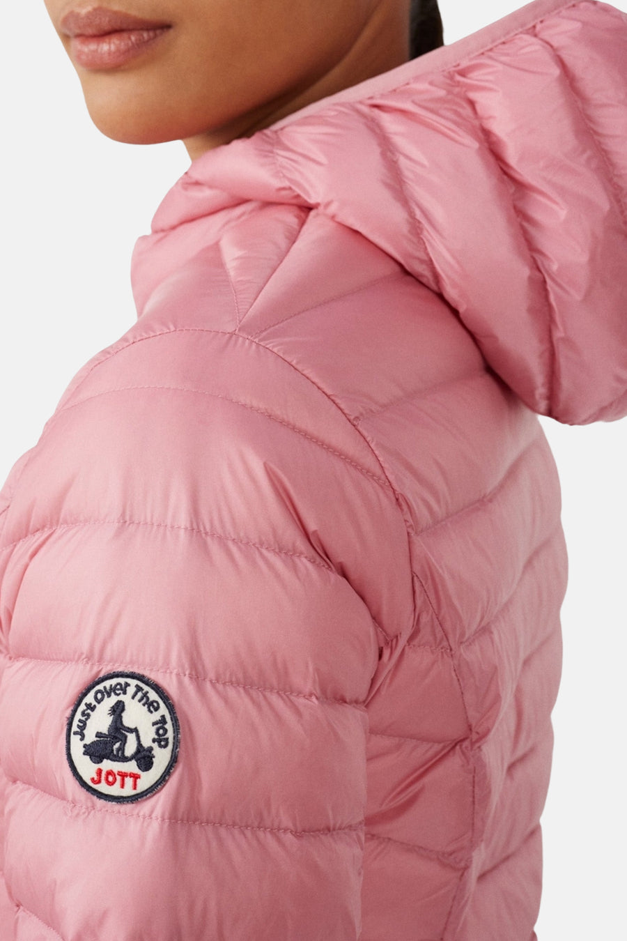 Veste de pluie rose de JOTT avec capuche, motif matelassé et patch logo sur la manche.