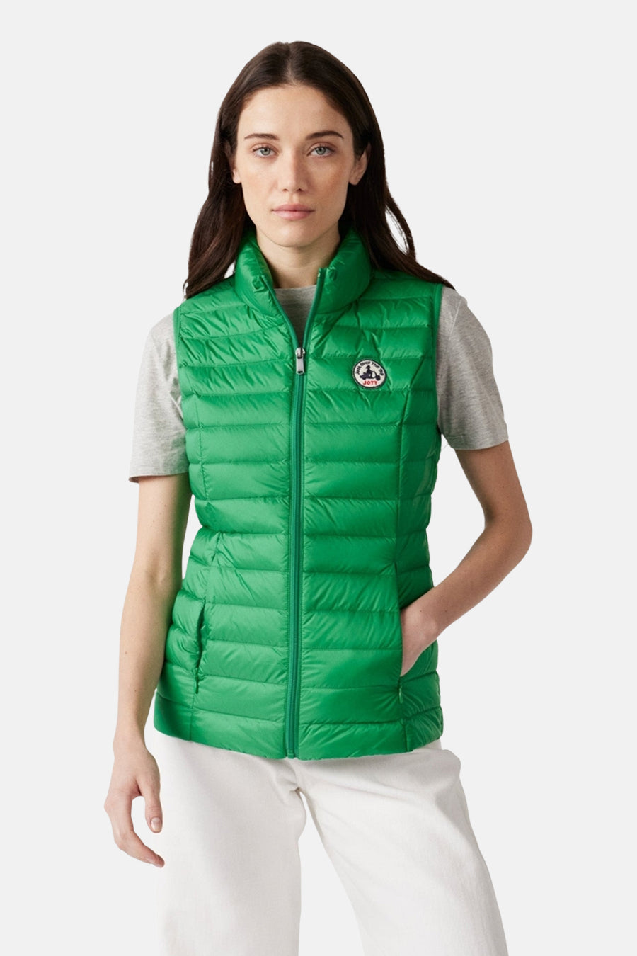 Groen mouwloos gewatteerd vest van JOTT, gedragen met een grijs T-shirt en een witte broek, van achteren gezien.