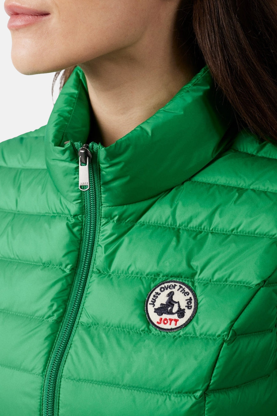 Groen mouwloos vest van JOTT, met ritssluiting en ronde badge op de borst.