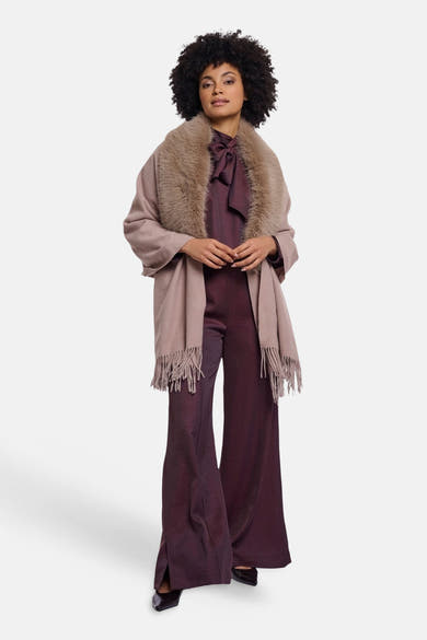 Beige wool-blend scarf with fringe and faux fur trim, worn by model in full-length lifestyle view with burgundy jumpsuit and black heels