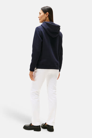 Blauwe hoodie van TOMMY HILFIGER, met capuchon en gedragen met een witte broek en zwarte schoenen.
