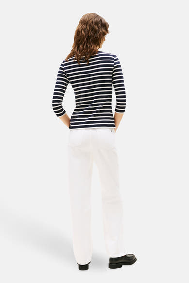 Blauw gestreept T-shirt van TOMMY JEANS, gedragen met een witte broek en zwarte schoenen.
