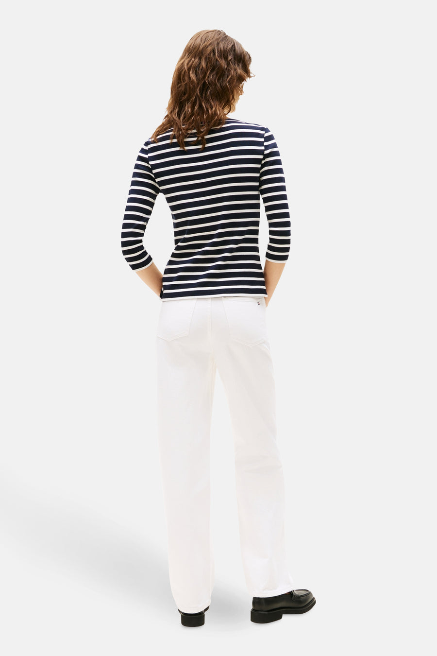 Blauw gestreept T-shirt van TOMMY JEANS, gedragen met een witte broek en zwarte schoenen.