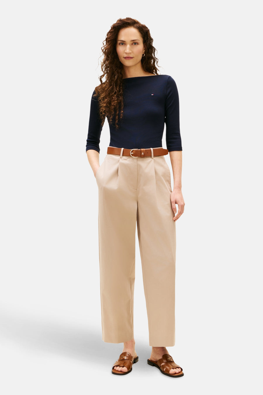 Donkerblauwe T-shirt met driekwartmouwen van TOMMY JEANS, gedragen met een bruine riem en een beige broek.