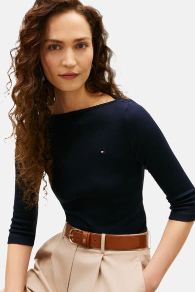Donkerblauwe T-shirt met 3/4 mouwen van Tommy Jeans, gedragen met een bruine leren riem en een beige geplooide broek.