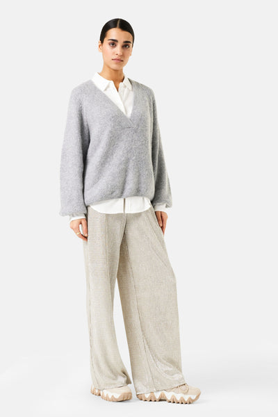Pull à col en V gris de GARCIA, porté sur une chemise blanche avec un pantalon texturé brillant.
