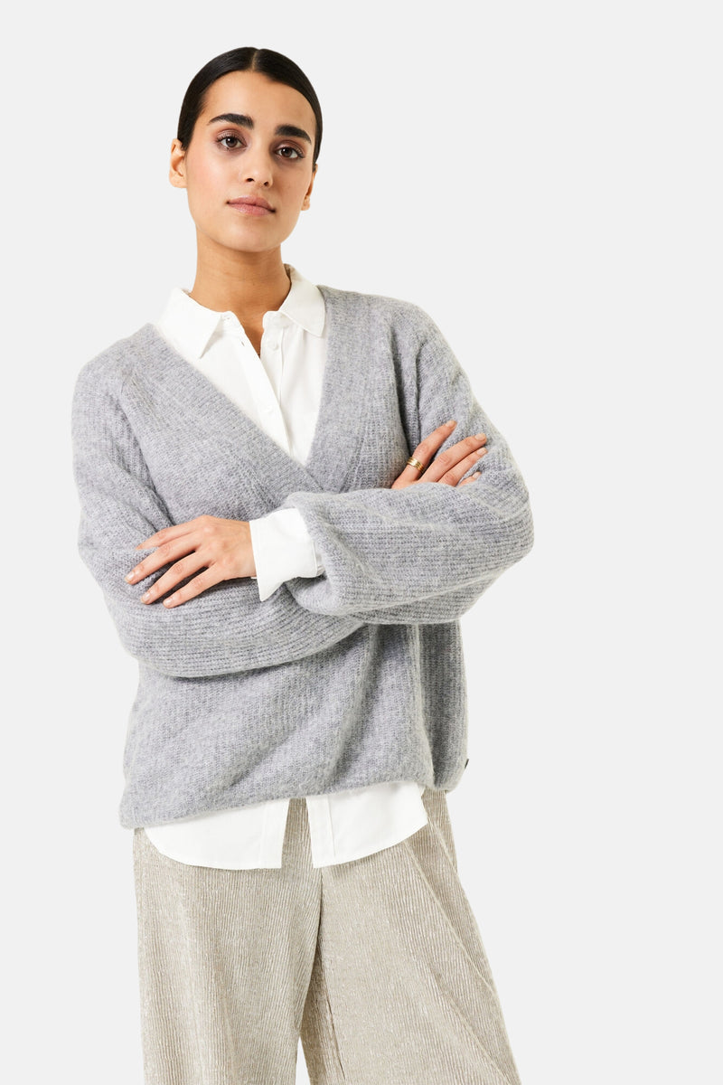 Pull à col en V gris de GARCIA, porté sur une chemise blanche avec un pantalon texturé.