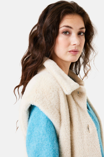 Veste sans manches écrue de GARCIA avec un col et une texture douce portée sur un pull bleu.