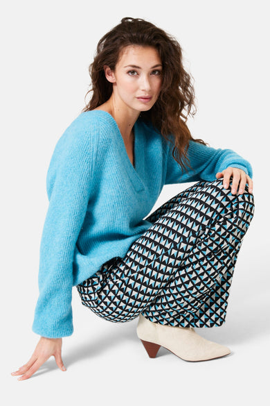 Pantalon noir à motif géométrique by GARCIA, porté avec un pull bleu et des bottines couleur crème.
