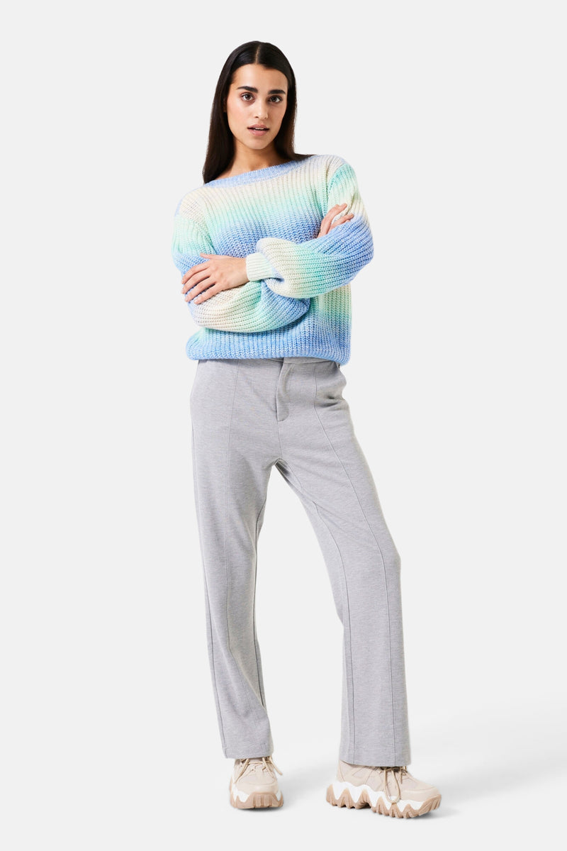 Pantalon gris de GARCIA, avec coutures verticales sur le devant et porté avec un pull multicolore.
