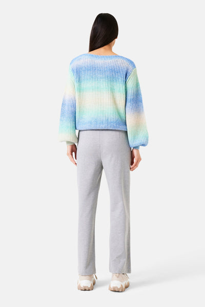 Pantalon gris de GARCIA, porté avec un pull en maille dégradée bleu et des baskets beiges à semelle épaisse.