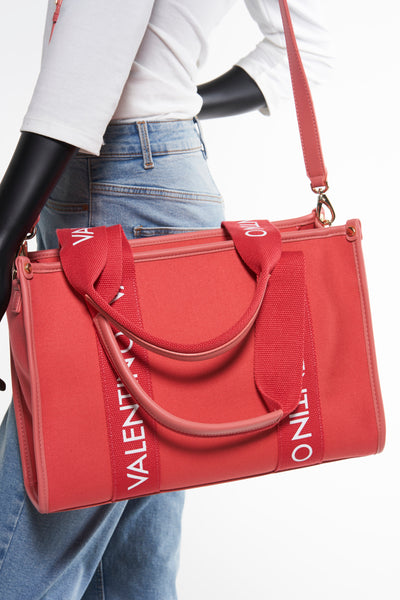 Oranje handtas van VALENTINO BAGS met schouderriem, gedragen met een spijkerbroek en een wit T-shirt.