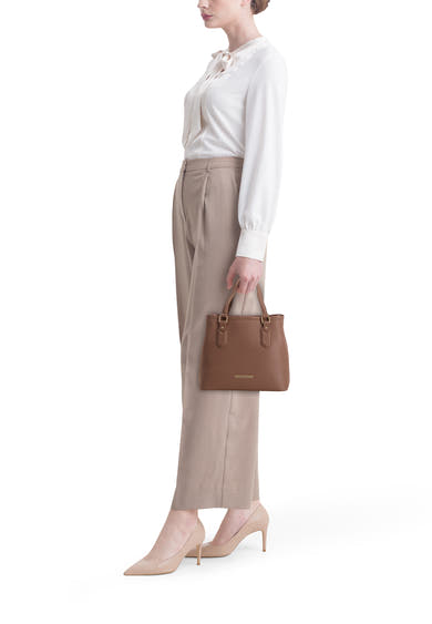 Sac à main marron en cuir de VALENTINO BAGS, porté avec un chemisier blanc et un pantalon beige.