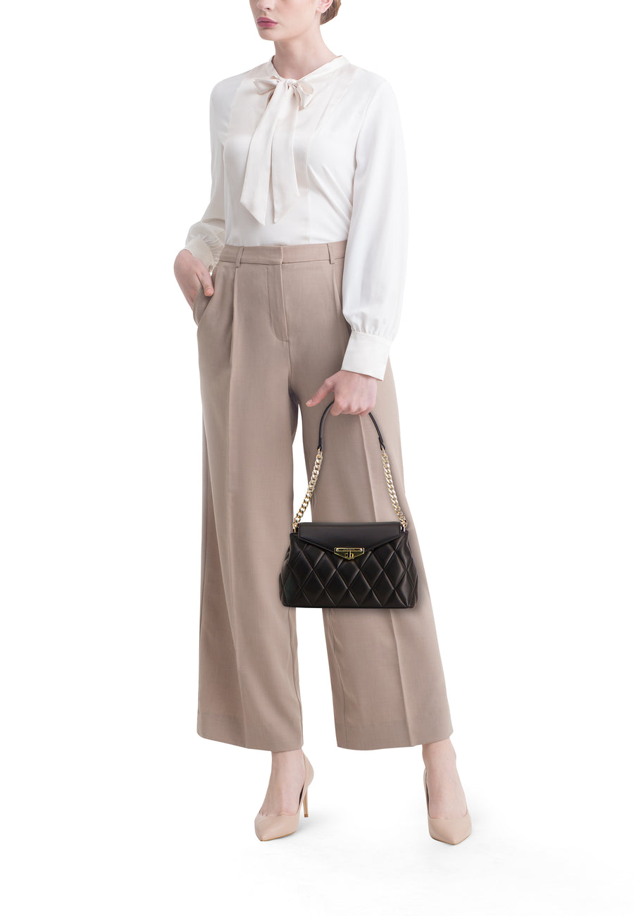 Zwarte VALENTINO BAGS schoudertas, met gouden ketting, gedragen met beige blouse en broek.