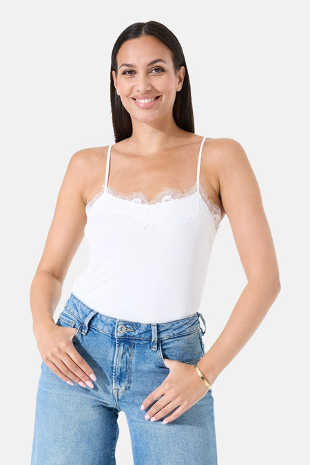 Débardeur blanc à fines bretelles de GARCIA, orné de dentelle délicate au décolleté, porté avec un jean taille haute.

