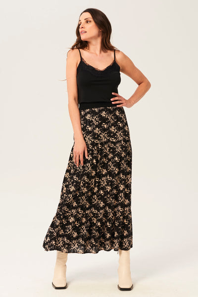 Top noir à fines bretelles de GARCIA, orné de dentelle et porté avec une jupe longue à motifs floraux.