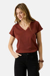Brick red short-sleeve V-neck knit top with ribbed trim, worn with black jeans and layered gold necklaces, front view