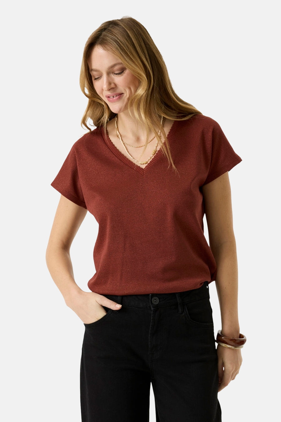 Brick red short-sleeve V-neck knit top with ribbed trim, worn with black jeans and layered gold necklaces, front view