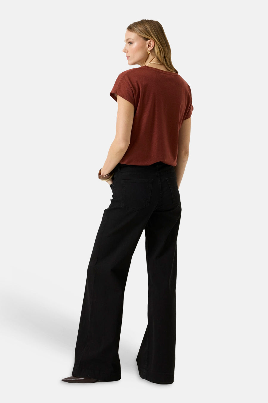 Brick red short-sleeve t-shirt with relaxed fit, shown from back on model wearing black wide-leg pants and brown shoes.