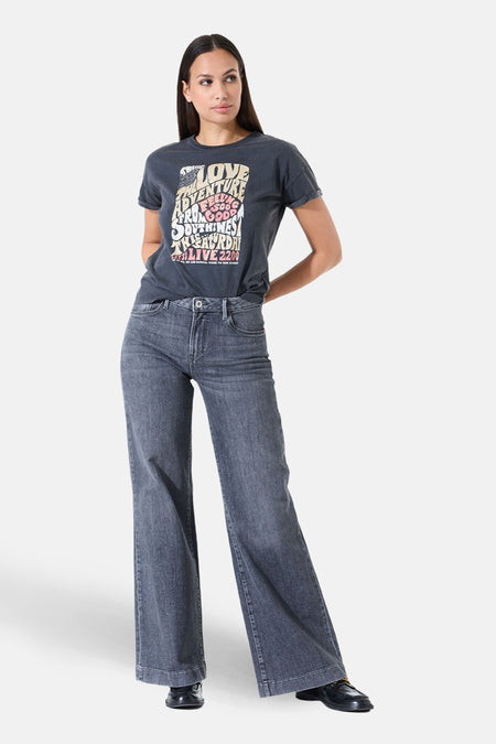 T-shirt gris à manches courtes de GARCIA, avec un imprimé graphique, porté avec un jean ample bleu-gris.
