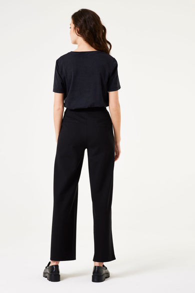 Pantalon noir par GARCIA, coupe droite, porté avec un t-shirt noir et des chaussures à plateforme.