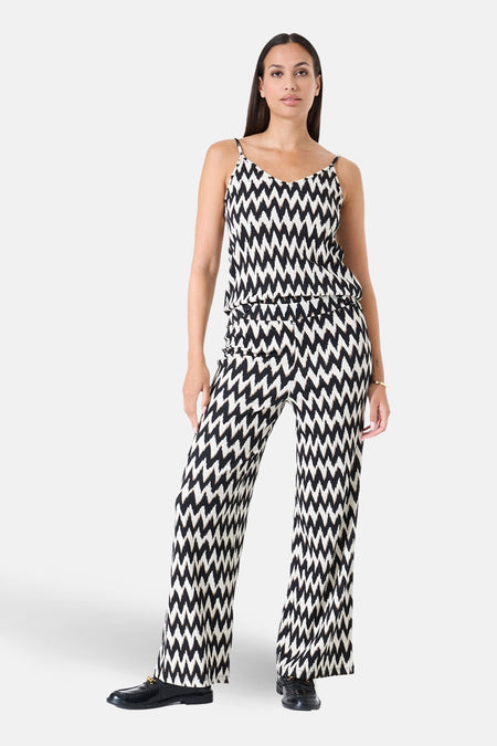 Pantalon multicolore GARCIA, avec motif zigzag noir et blanc sur l'ensemble, porté avec des chaussures noires classiques.
