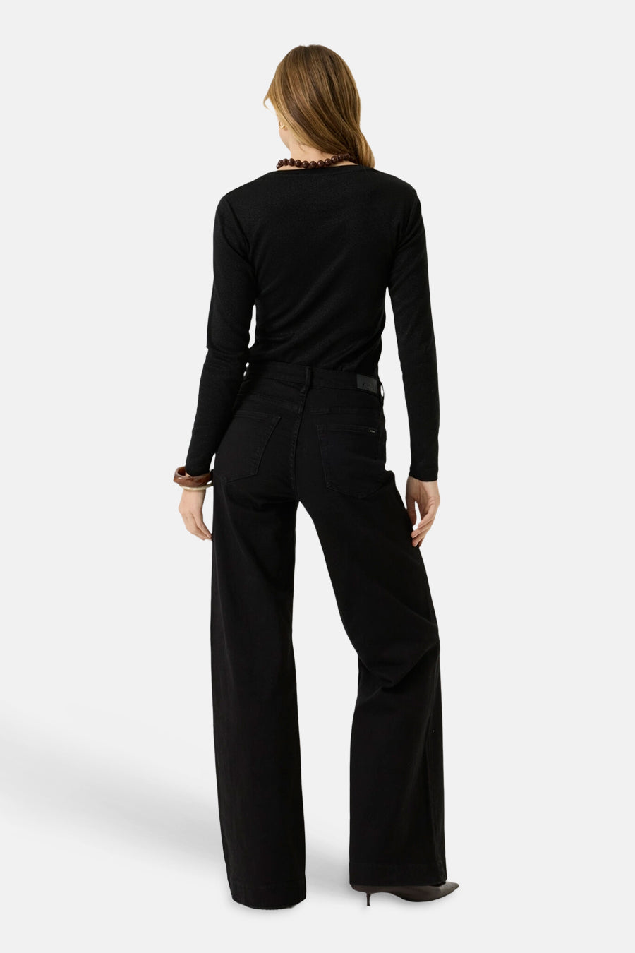 Black long-sleeve t-shirt with ribbed texture, back view, worn with black wide-leg pants and beaded necklace