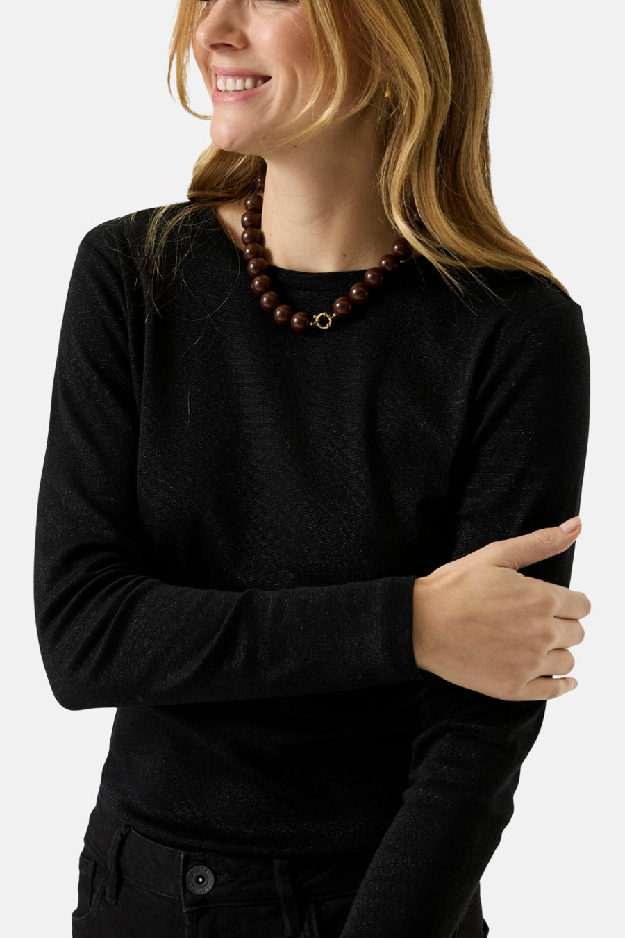 Black long-sleeve t-shirt with ribbed texture and round neckline, worn by model with brown beaded necklace, side view.