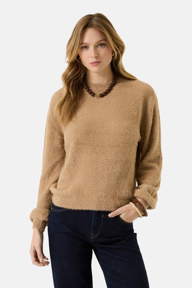 Beige fuzzy crewneck sweater with ribbed cuffs and hem, worn with dark jeans and beaded necklace, front view
