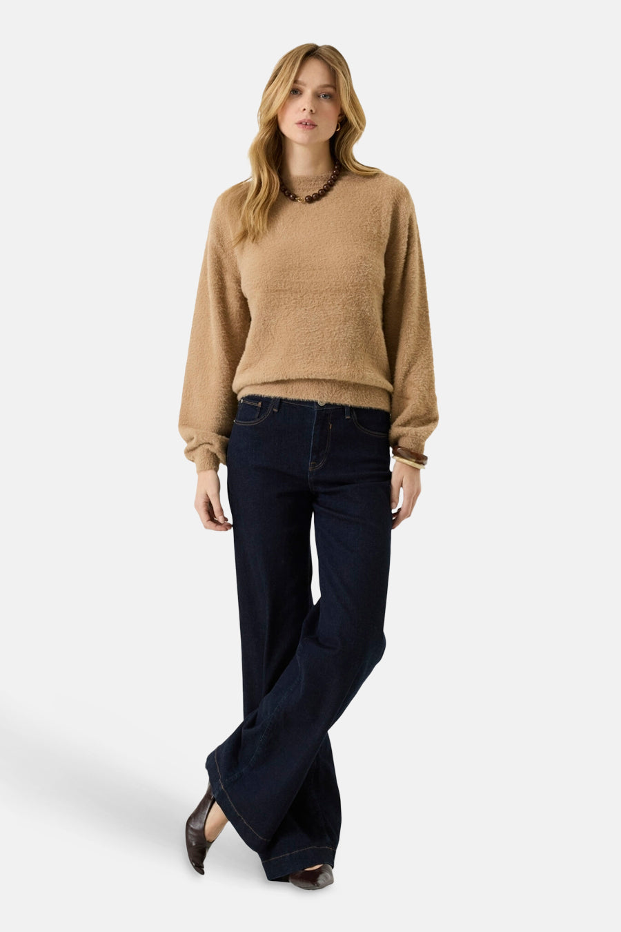 Beige fuzzy crewneck sweater with long sleeves, worn with dark blue wide-leg jeans and brown boots, full-length front view