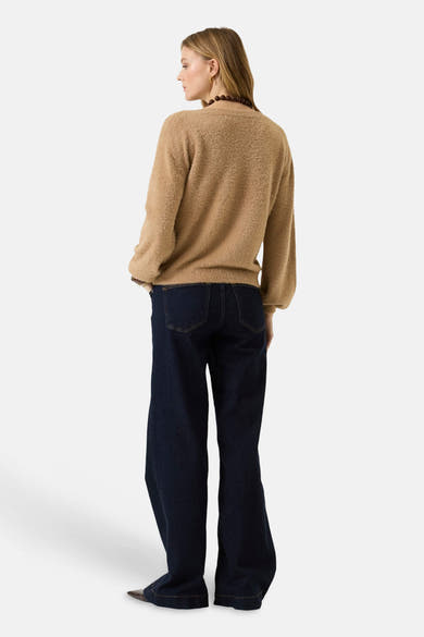 Beige O-neck sweater with soft textured knit, shown from back on model wearing dark jeans and beaded necklace