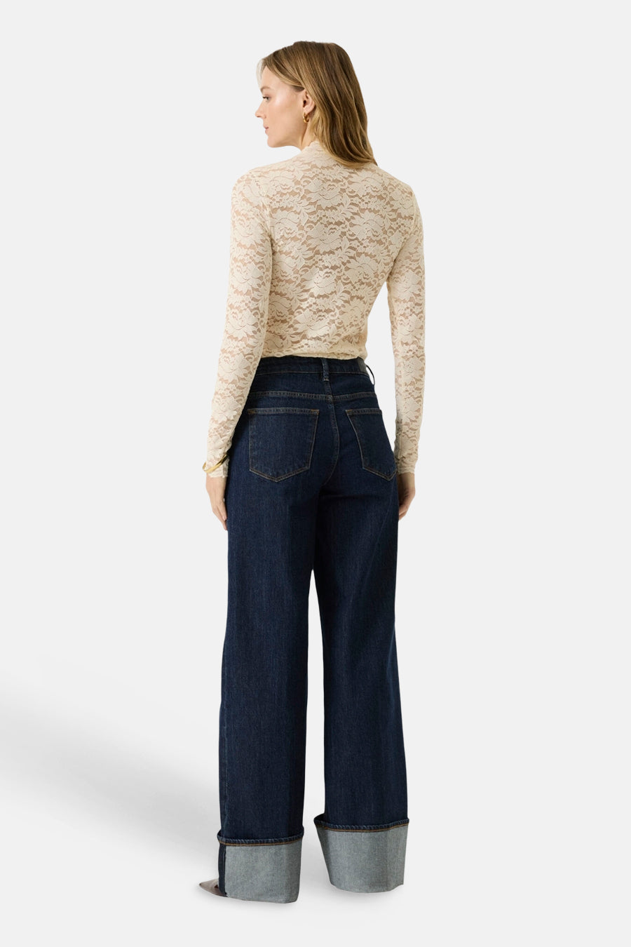 Ecru long-sleeve lace top from back view, featuring floral pattern and fitted silhouette with dark denim pants.