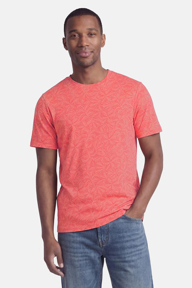 Coral short-sleeve t-shirt with floral pattern, worn by model in front view with blue jeans