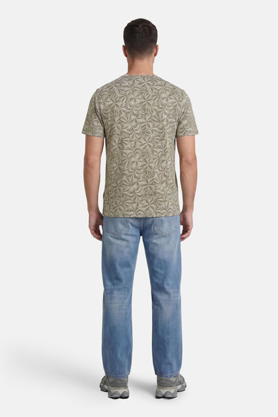 Multicolored short-sleeve t-shirt with leaf pattern, back view, worn with light blue jeans and gray sneakers