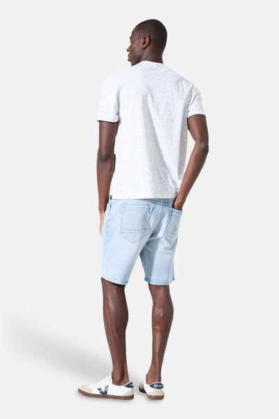 T-shirt blanc à manches courtes de GARCIA, avec motif imprimé clair sur l'ensemble, porté avec un short en jean.