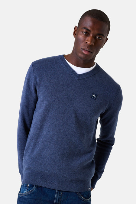 Blauwe V-hals trui van GARCIA, gedragen over een wit T-shirt, met een klein logo op de borst en een donkerblauwe jeans.