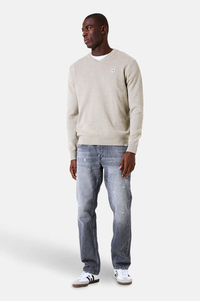 Kaki V-hals trui van GARCIA, gedragen over een wit T-shirt met een lichtgrijze jeans en sneakers.