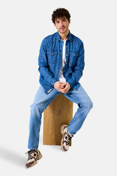 Middelblauwe spijkerblouse van GARCIA, gedragen open over een wit T-shirt en een verbleekte spijkerbroek.