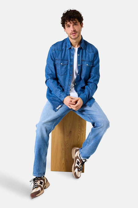 Middelblauwe spijkerblouse van GARCIA, gedragen open over een wit T-shirt en een verbleekte spijkerbroek.